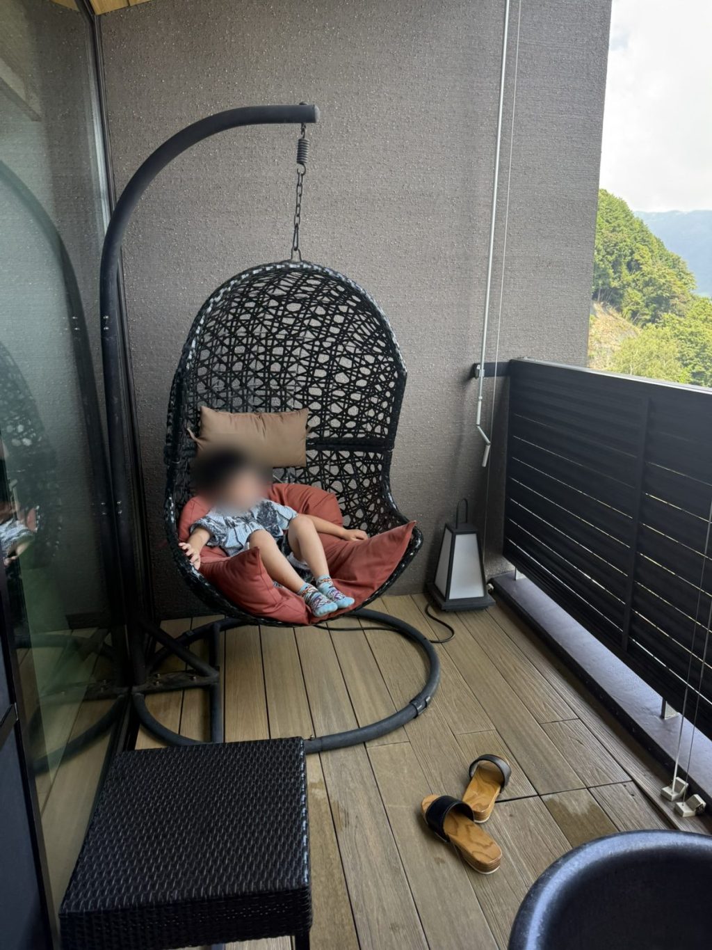 バルコニーのハンギングチェアに座る子ども
